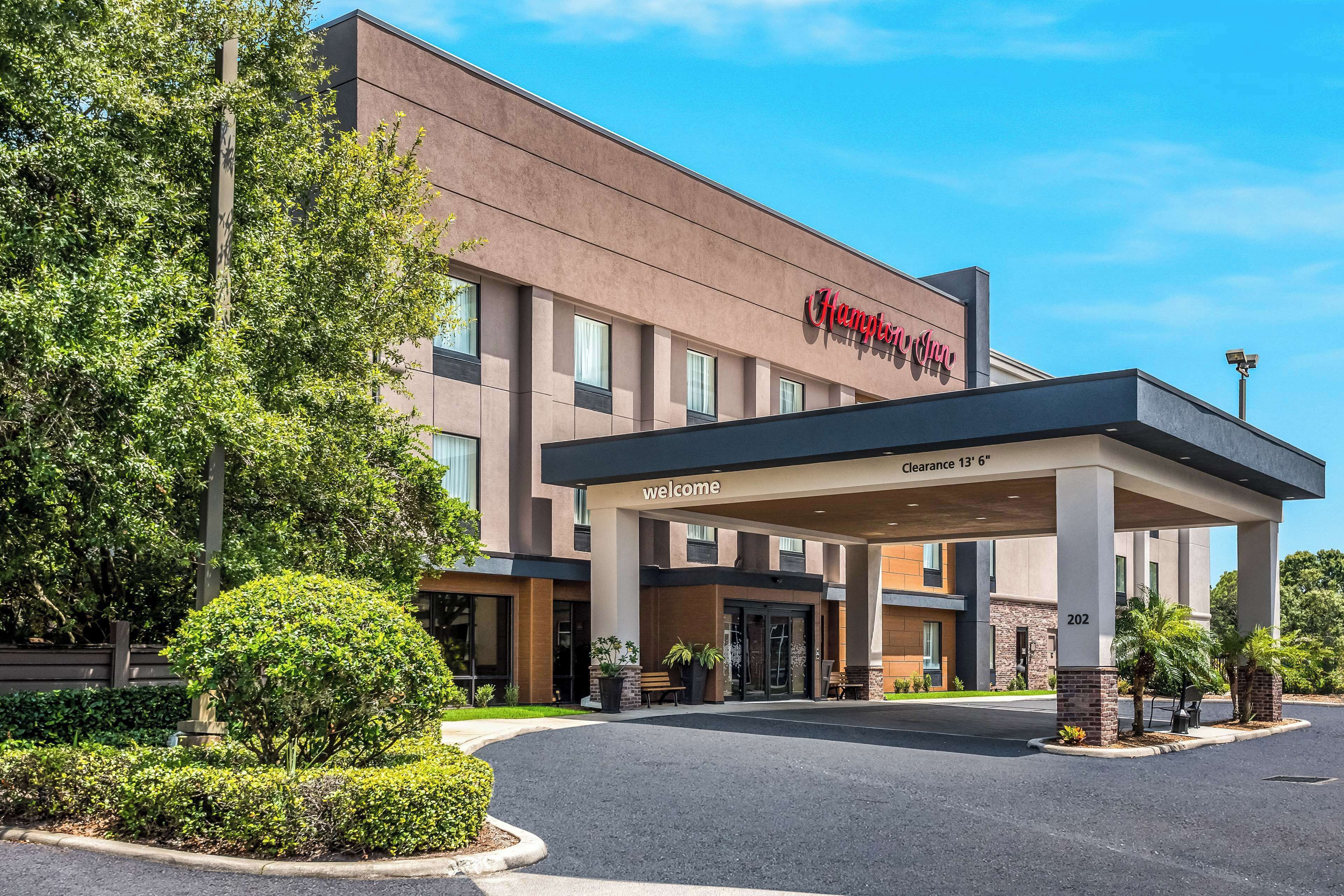 A Hampton Inn hotel with a covered entrance, clear signage, and a landscaped driveway.