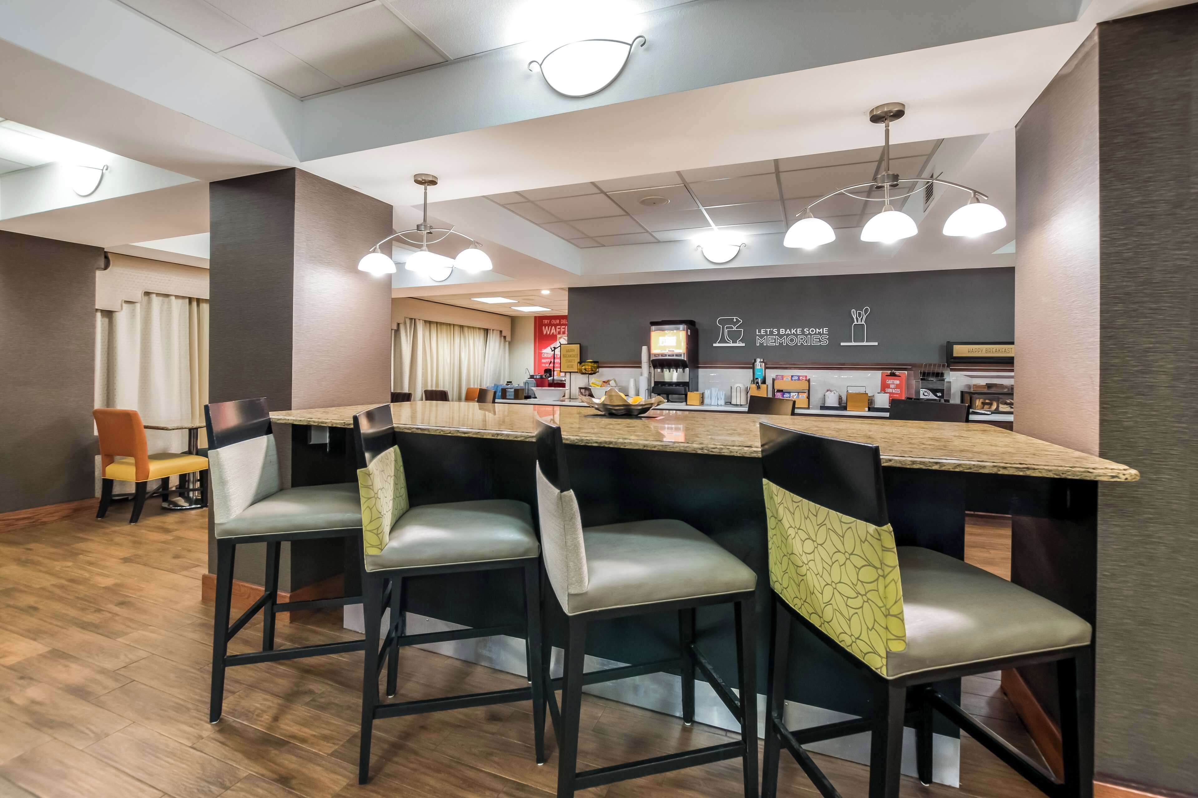Un área de cocina moderna con una isla central, taburetes de bar y una cafetera.