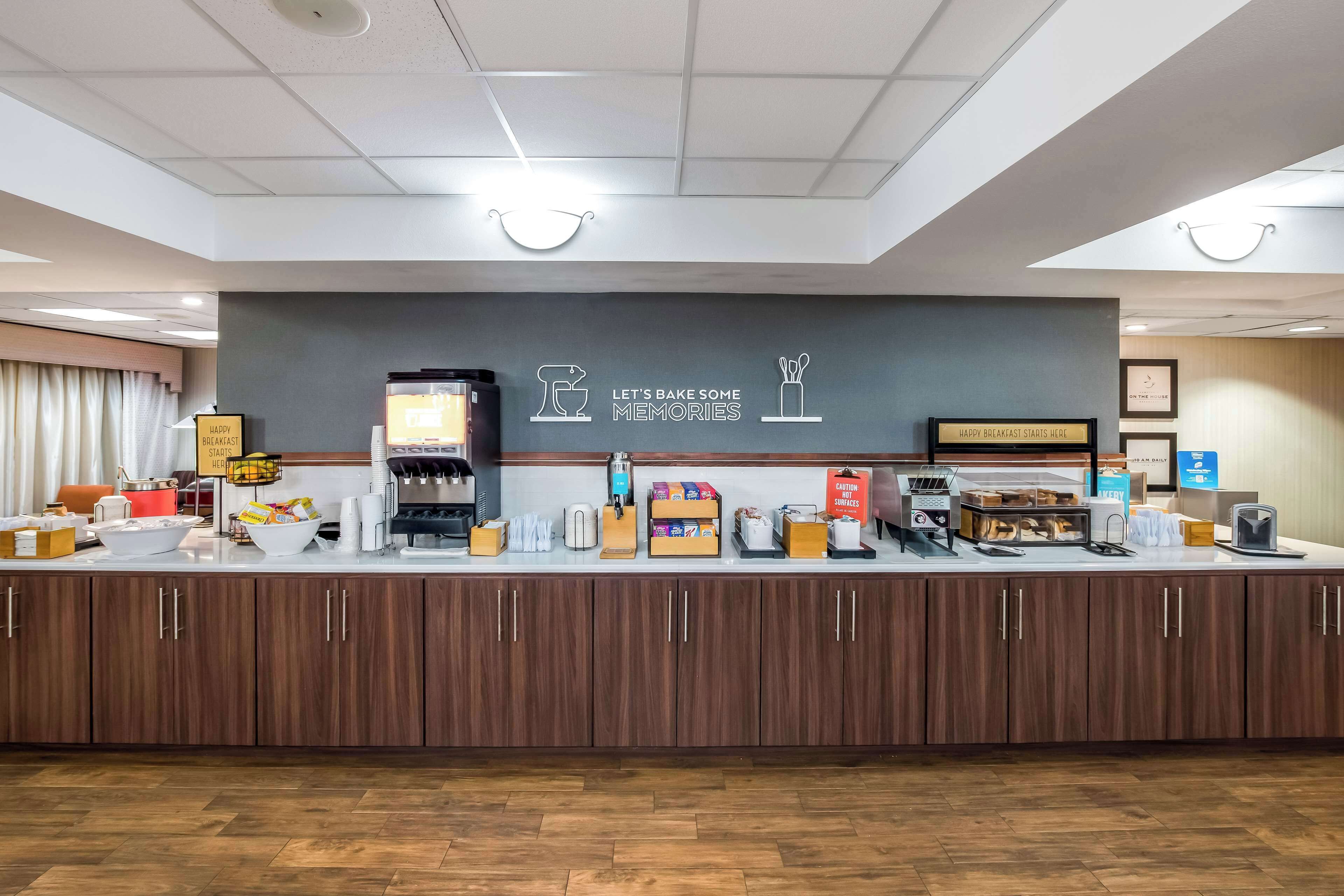 A breakfast bar with a sign that reads "Let's bake some memories." There are various breakfast items and a coffee machine on the counter.