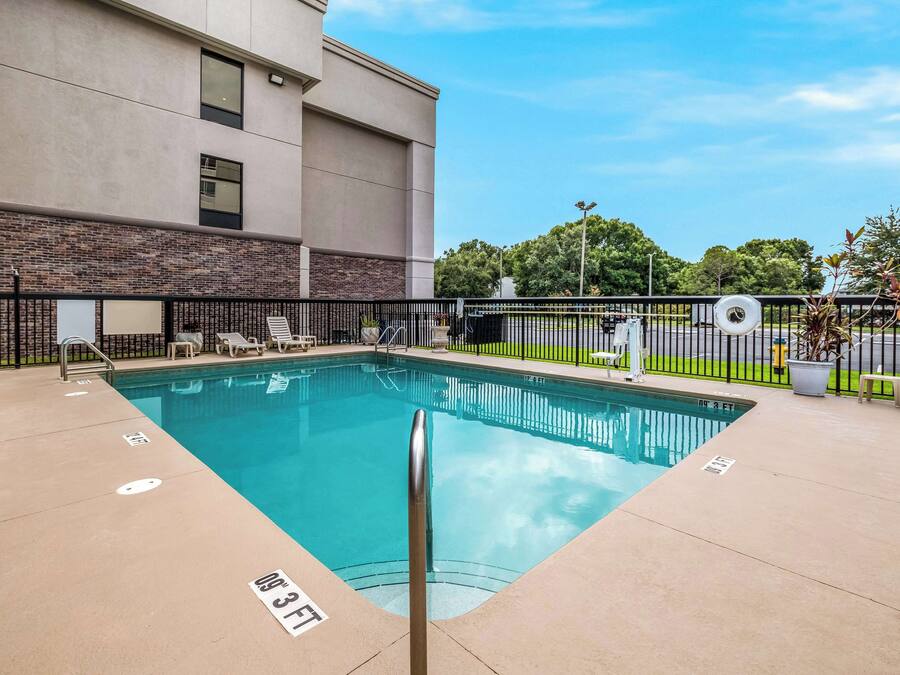 A rectangular indoor pool with a metal safety railing, surrounded by a black fence.