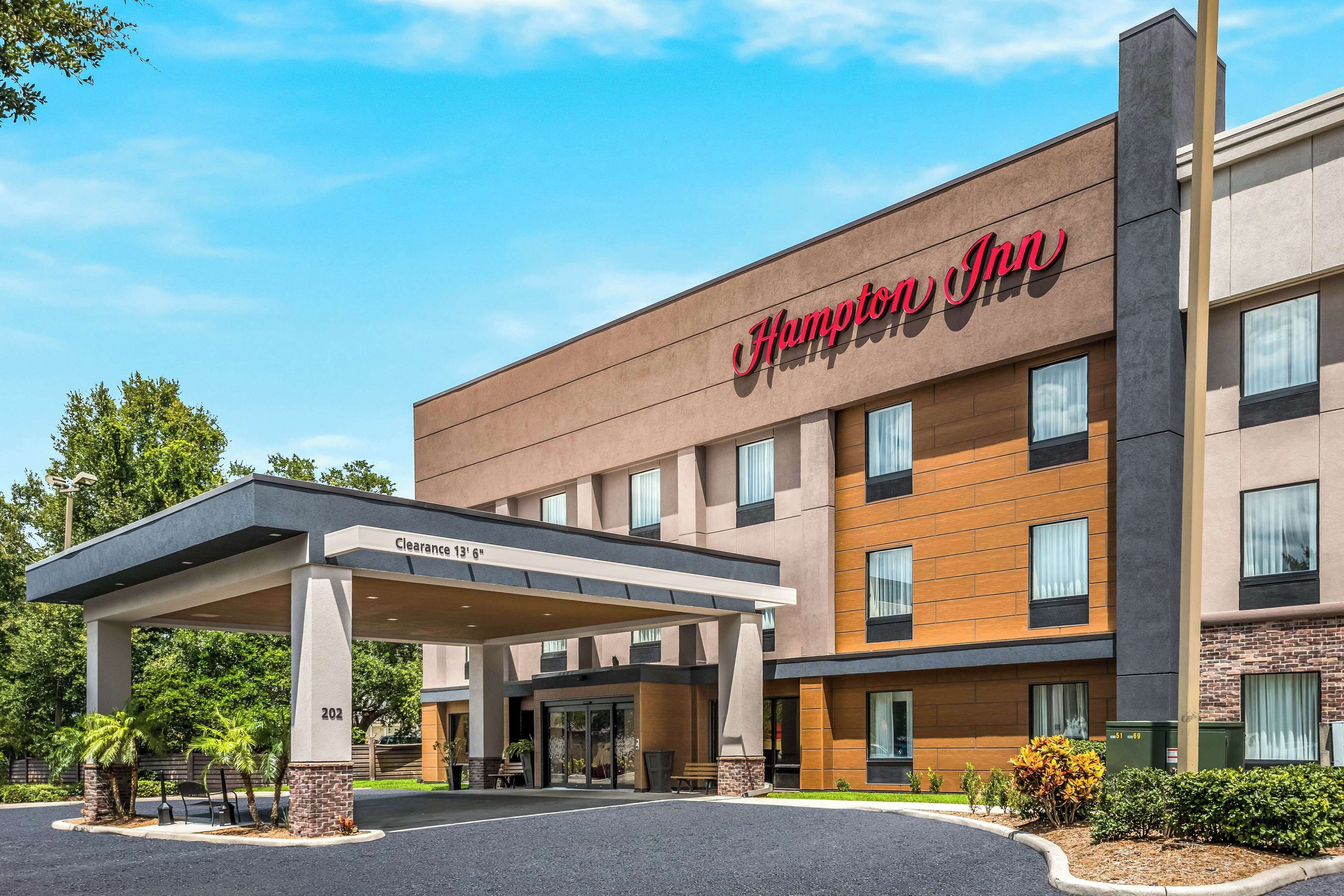 A Hampton Inn hotel with a covered entrance, clear signage, and a parking area.