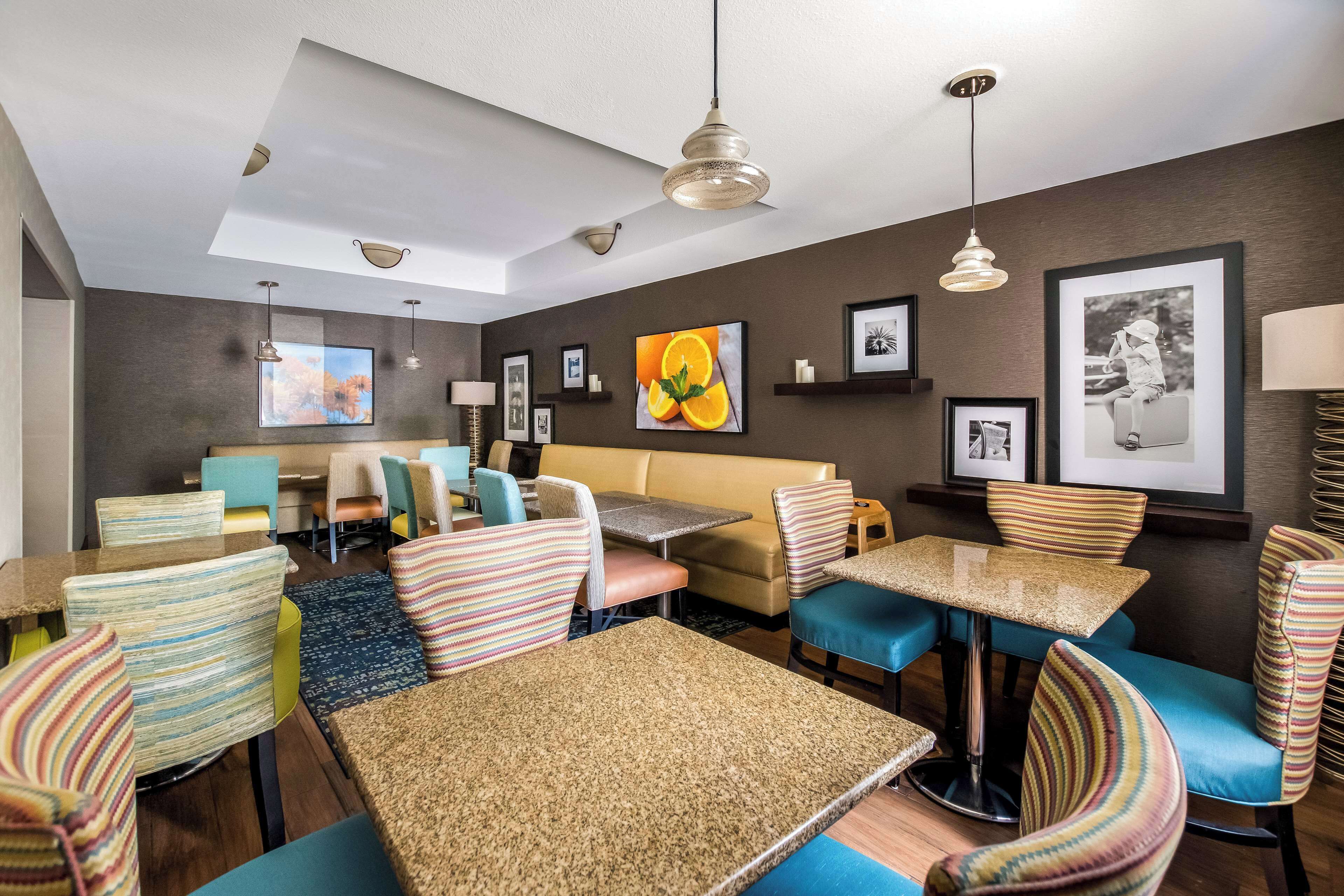 A hotel room with a dining area, a sofa, striped chairs, and a ceiling fan.