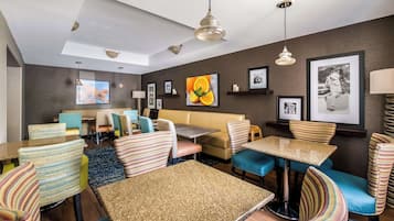 A hotel room with a dining area, a sofa, striped chairs, and a ceiling fan.