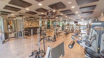 A gym with various exercise equipment, mirrors, and a wooden floor.