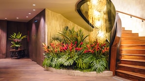 A modern interior with a curved staircase, a wooden floor, and a wall-mounted light fixture. - InterContinental Medellin - Movich by IHG (Medellín)
