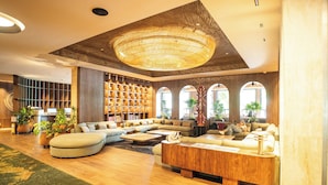 A spacious lobby with a large seating area, a wooden reception desk, and a decorative ceiling light. - InterContinental Medellin - Movich by IHG (Medellín)