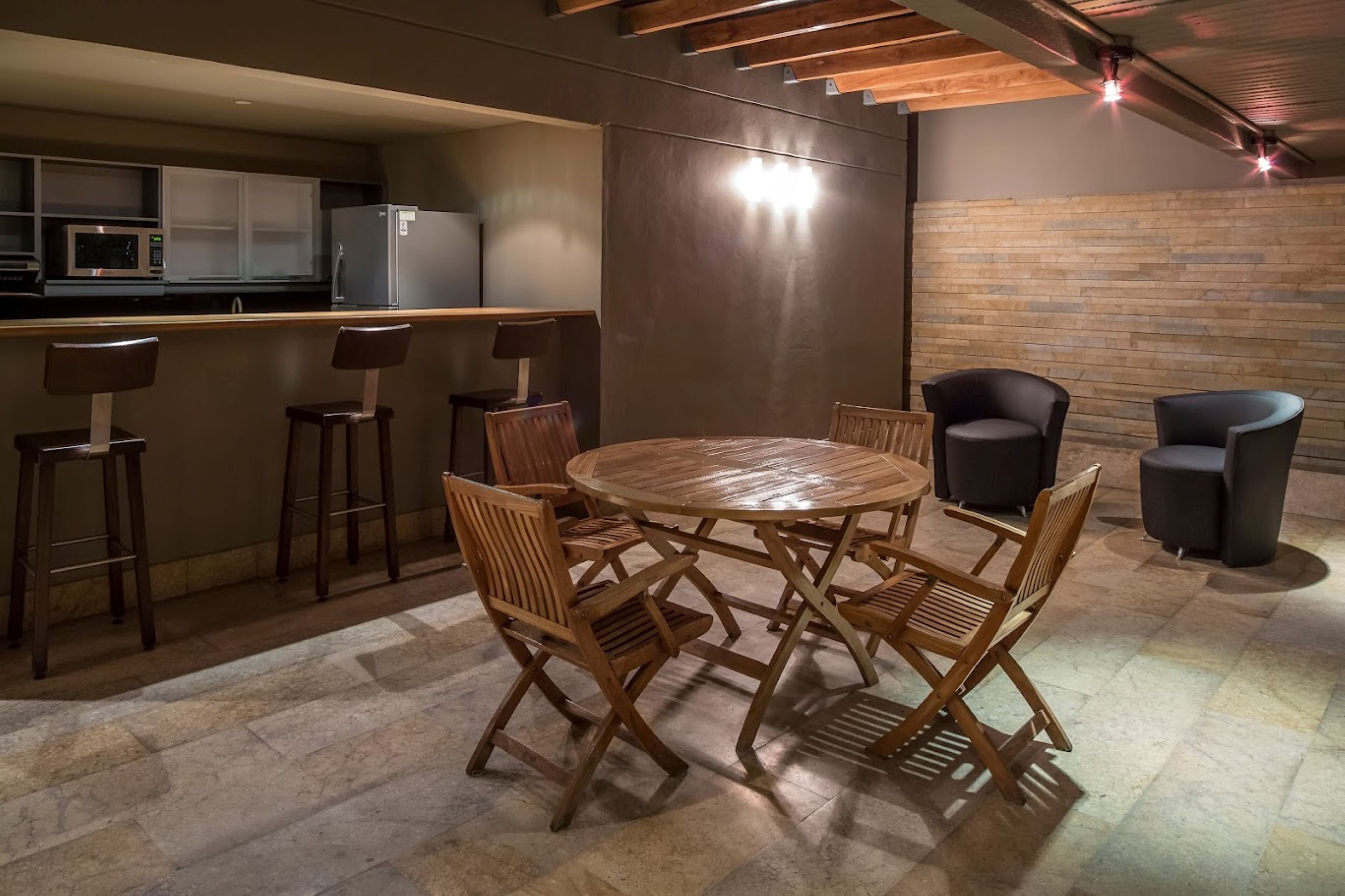 A modern kitchen with a bar area, wooden dining table, and chairs.