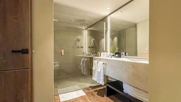 A modern bathroom with a large mirror, a shower, and a vanity with a sink and towel rack.