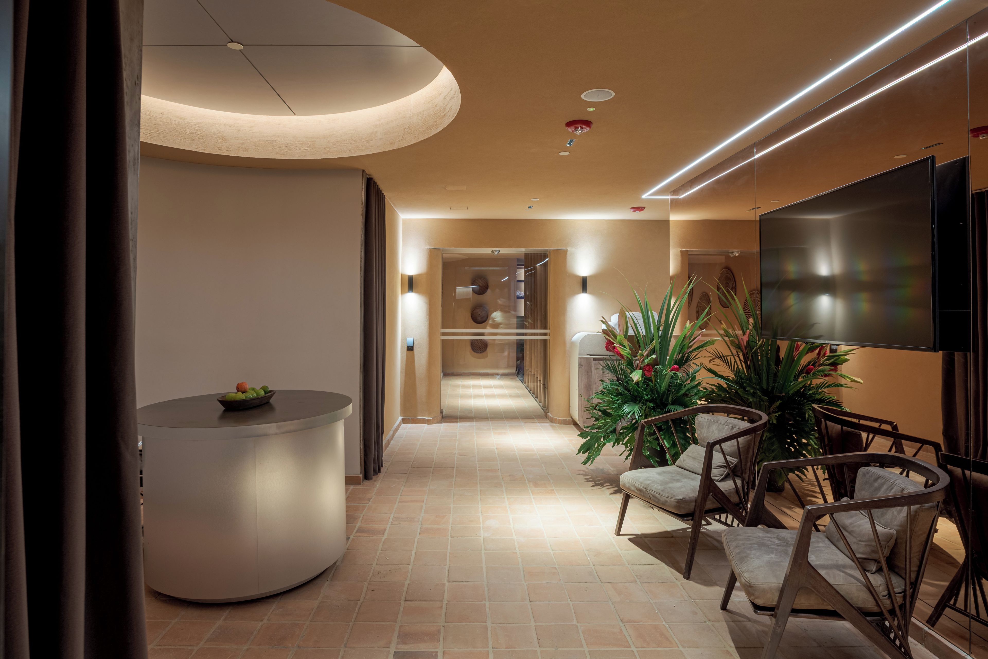 Eine moderne Hotelhalle mit einer Rezeption, einer Sitzecke und einem großen Flachbildfernseher.