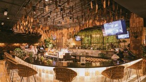 A bar area with a curved counter, wicker bar stools, and hanging wooden elements. - InterContinental Medellin - Movich by IHG (Medellín)