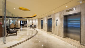 Un hall d’entrée moderne doté d’un sol incurvé, de murs en verre et d’un espace détente avec des fauteuils et des tables.