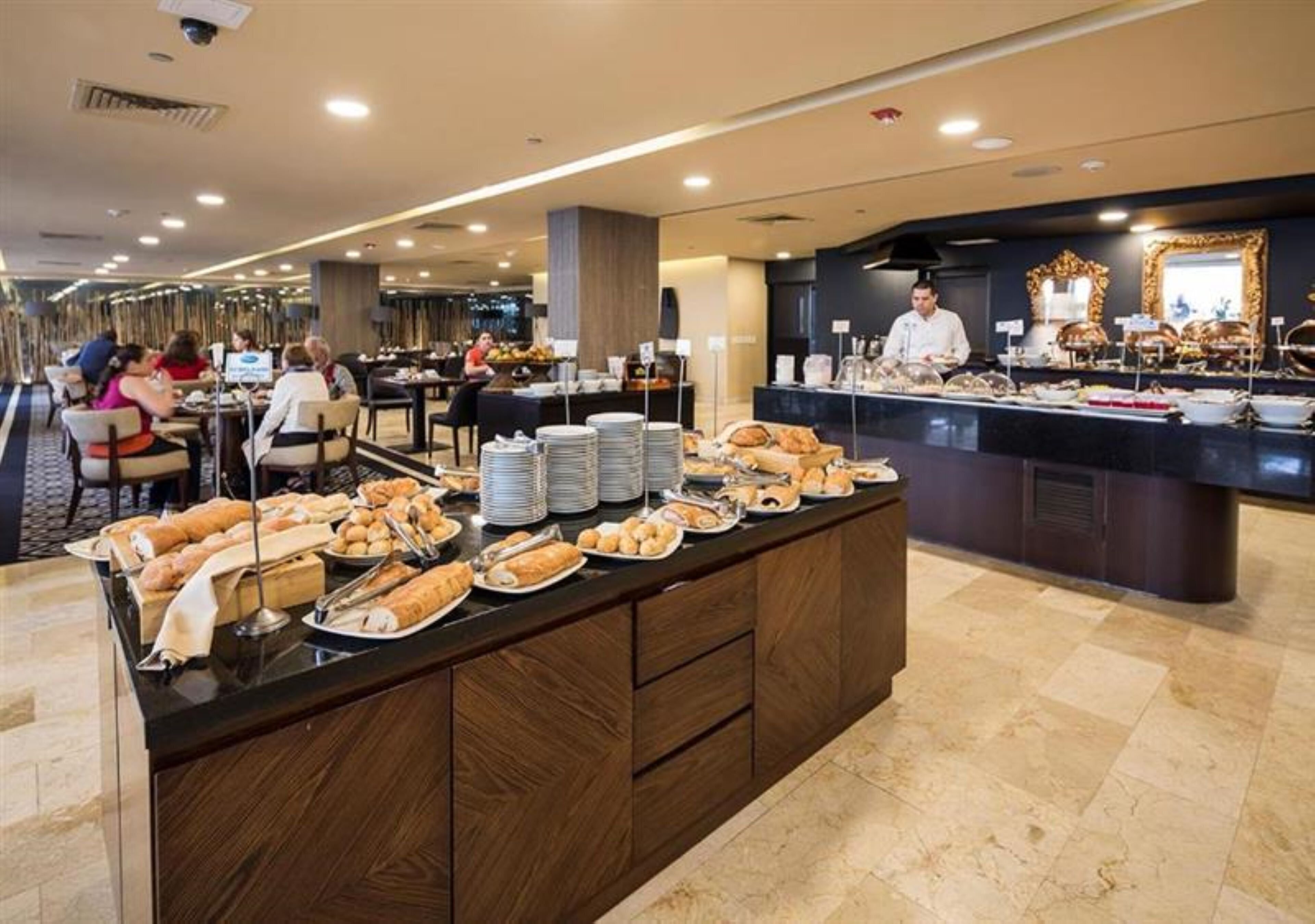 Zona de buffet amb diversos aliments i un taulell on hi ha un membre del personal.