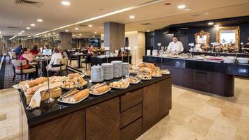 A buffet area with various food items and a counter with a staff member.