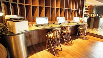 A modern reception desk with three computer stations, a printer, and a coffee machine.