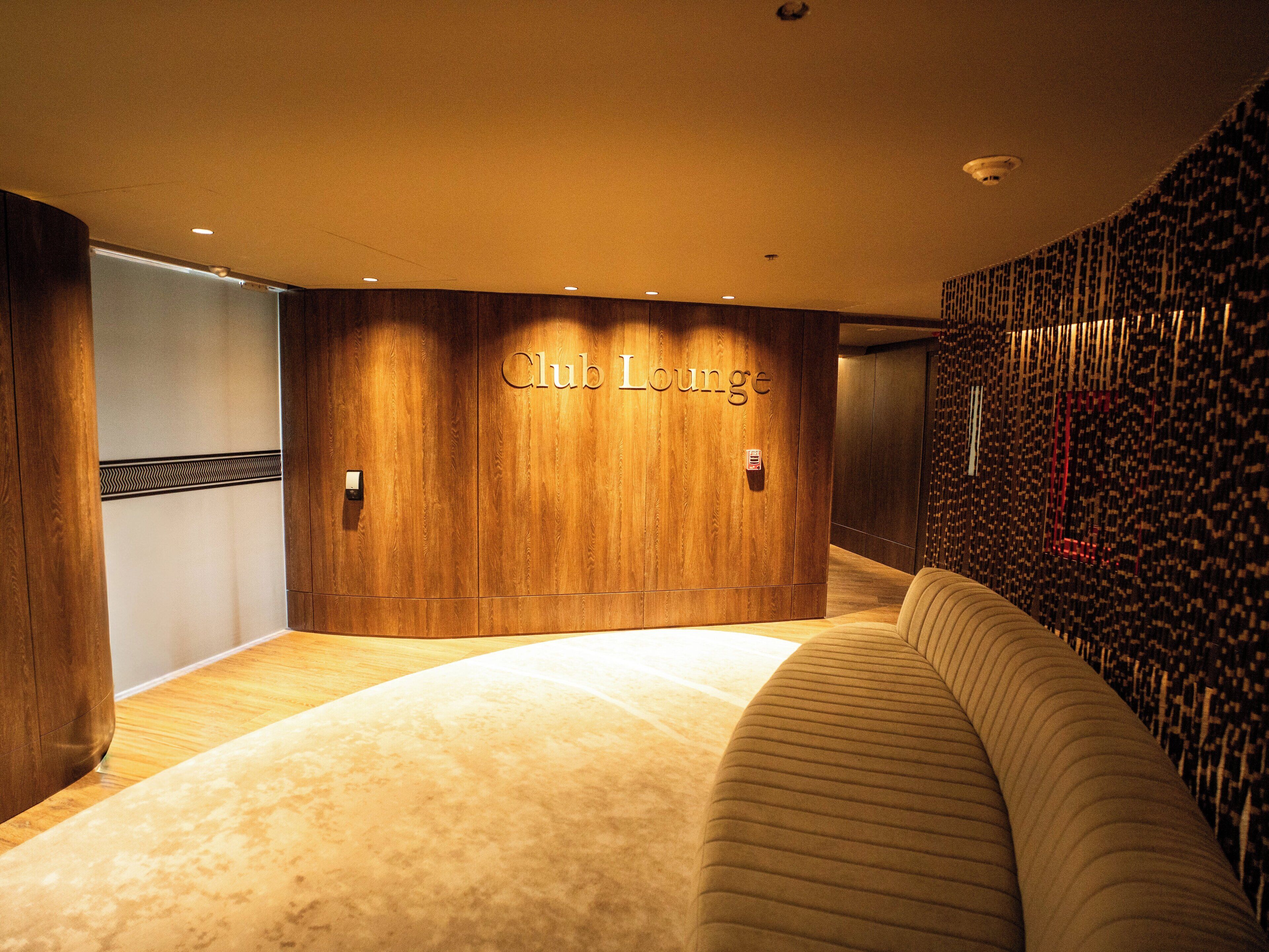 A Club Lounge with wooden paneling and a plush sofa.