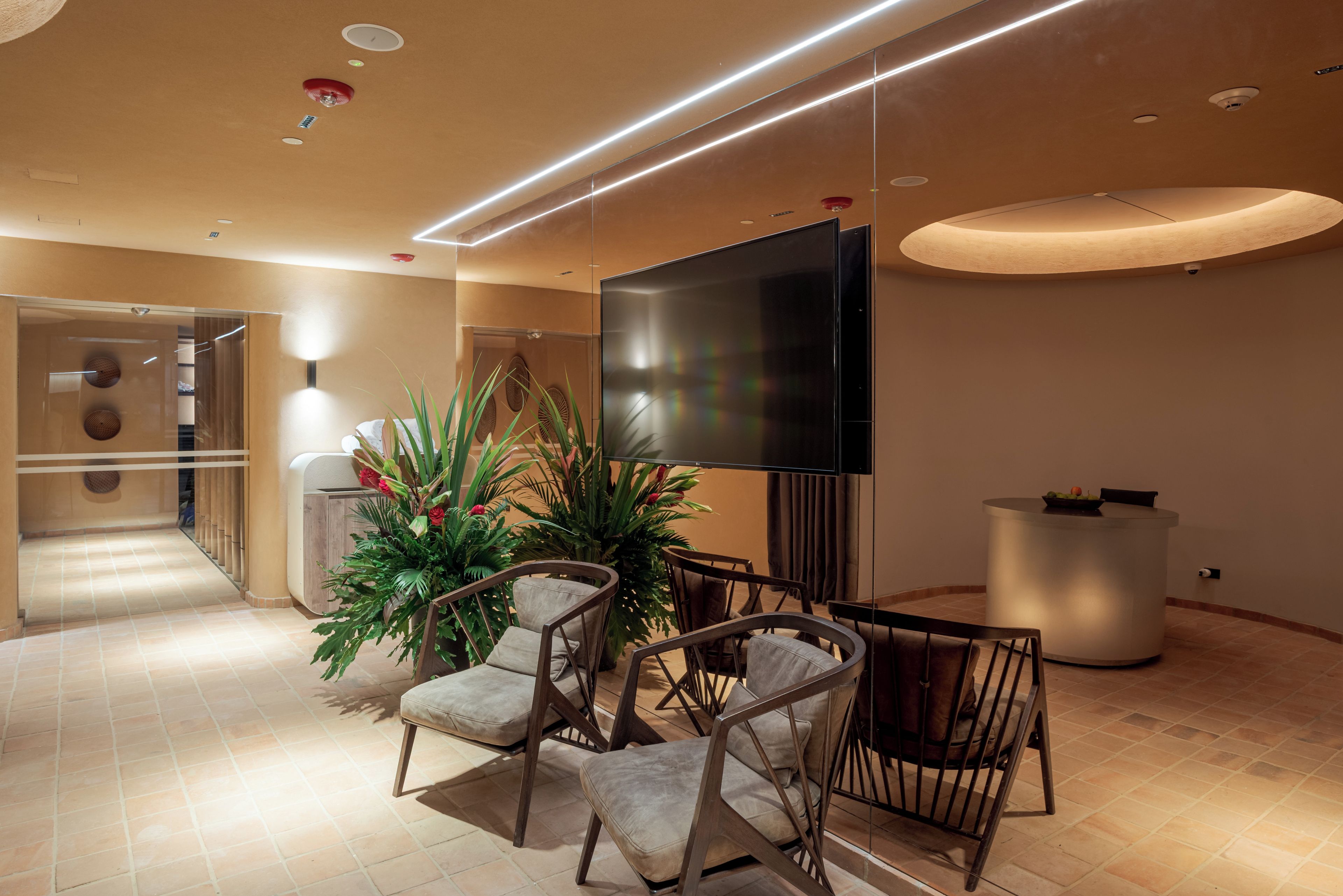 A modern lobby with a flat-screen TV, seating area with chairs, and a reception desk.