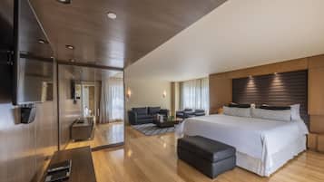 A modern hotel room with a large bed, a desk, a sofa, and a TV.