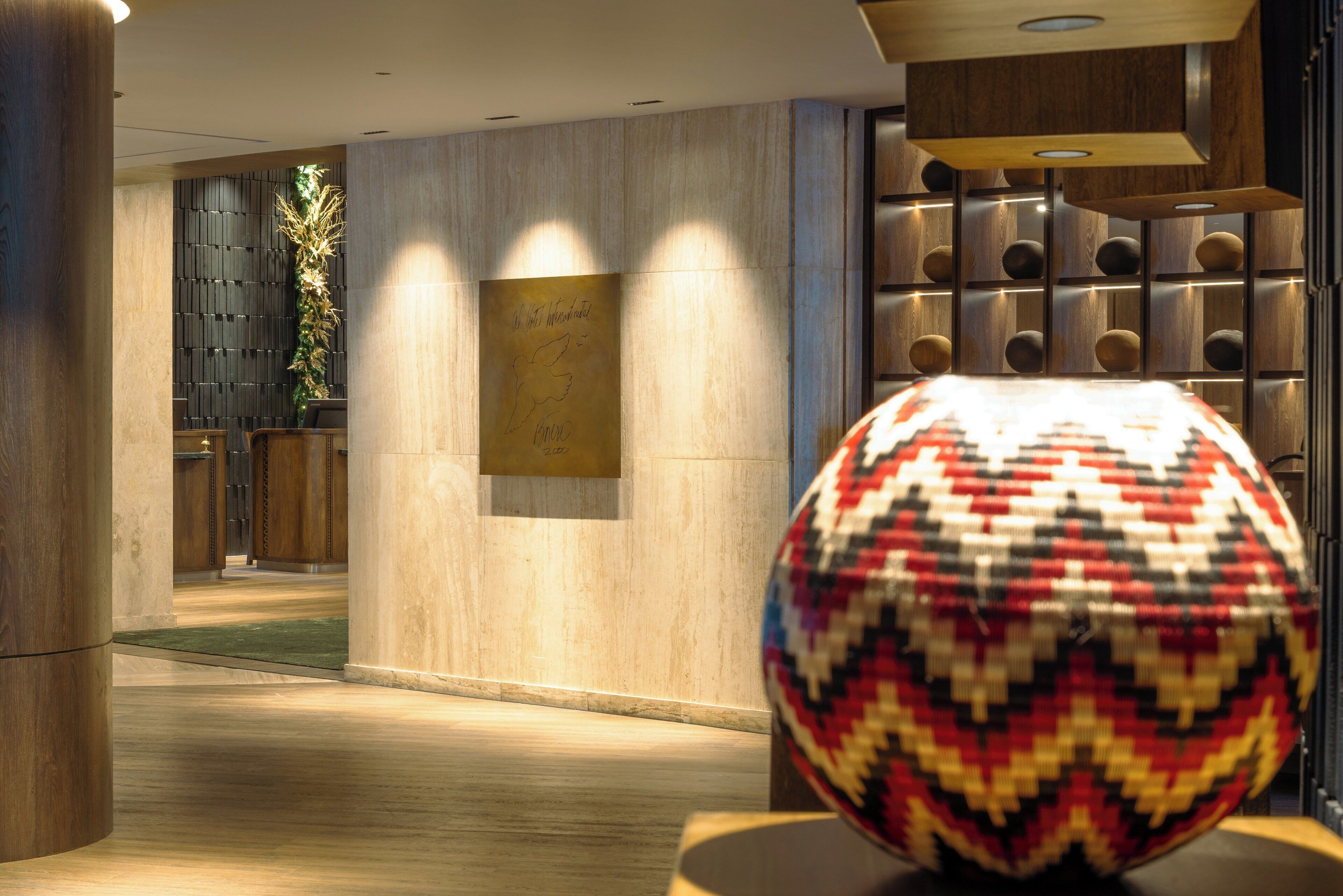 A modern interior with a wooden floor, a decorative wall with recessed lighting, and a patterned spherical object on a table.