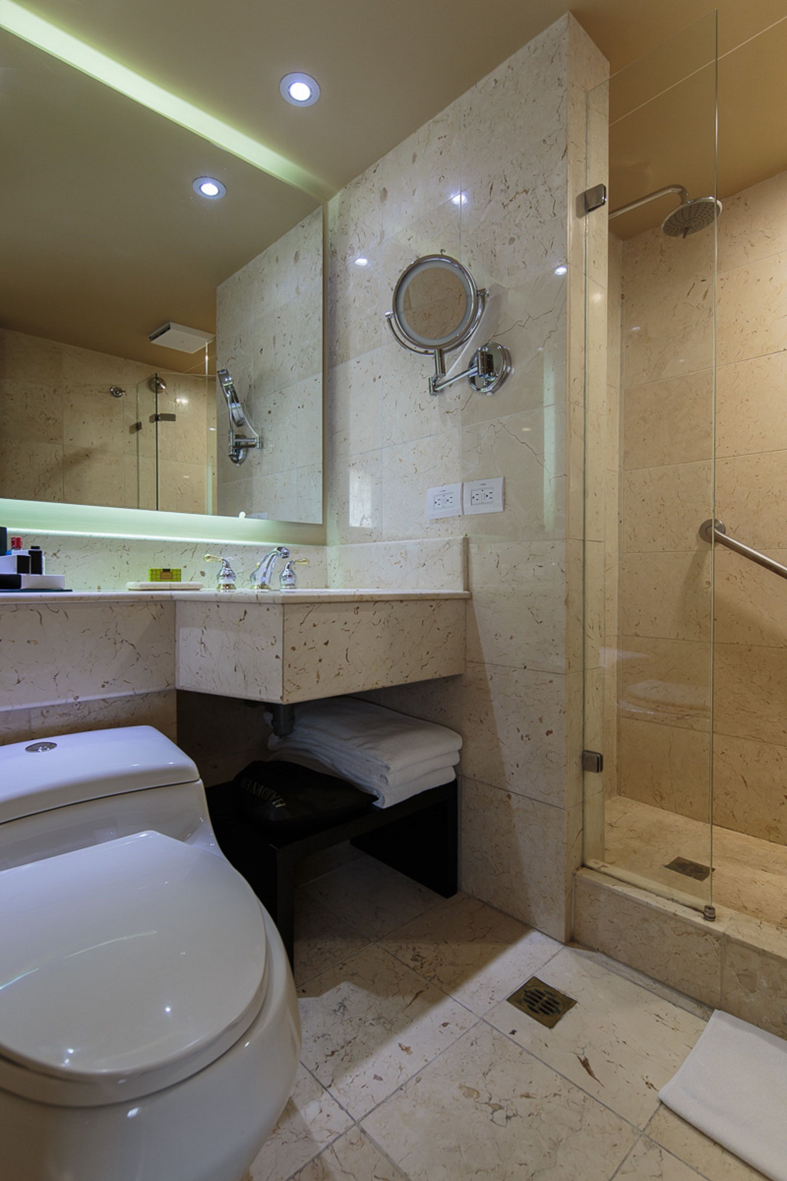 A modern bathroom with a toilet, sink, and glass-enclosed shower.