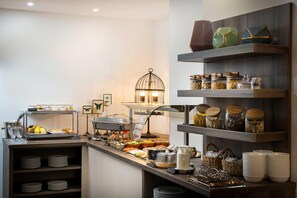 A breakfast buffet with various food items, a coffee station, and a decorative birdcage. - elaya hotel vienna city center, Trademark by Wyndham (Vienna)