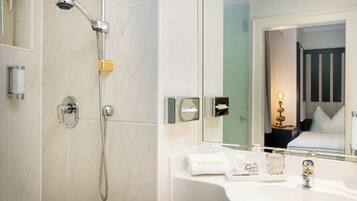 Ein Hotelbadezimmer mit Dusche, Waschbecken, Spiegel und Handtuchhalter.