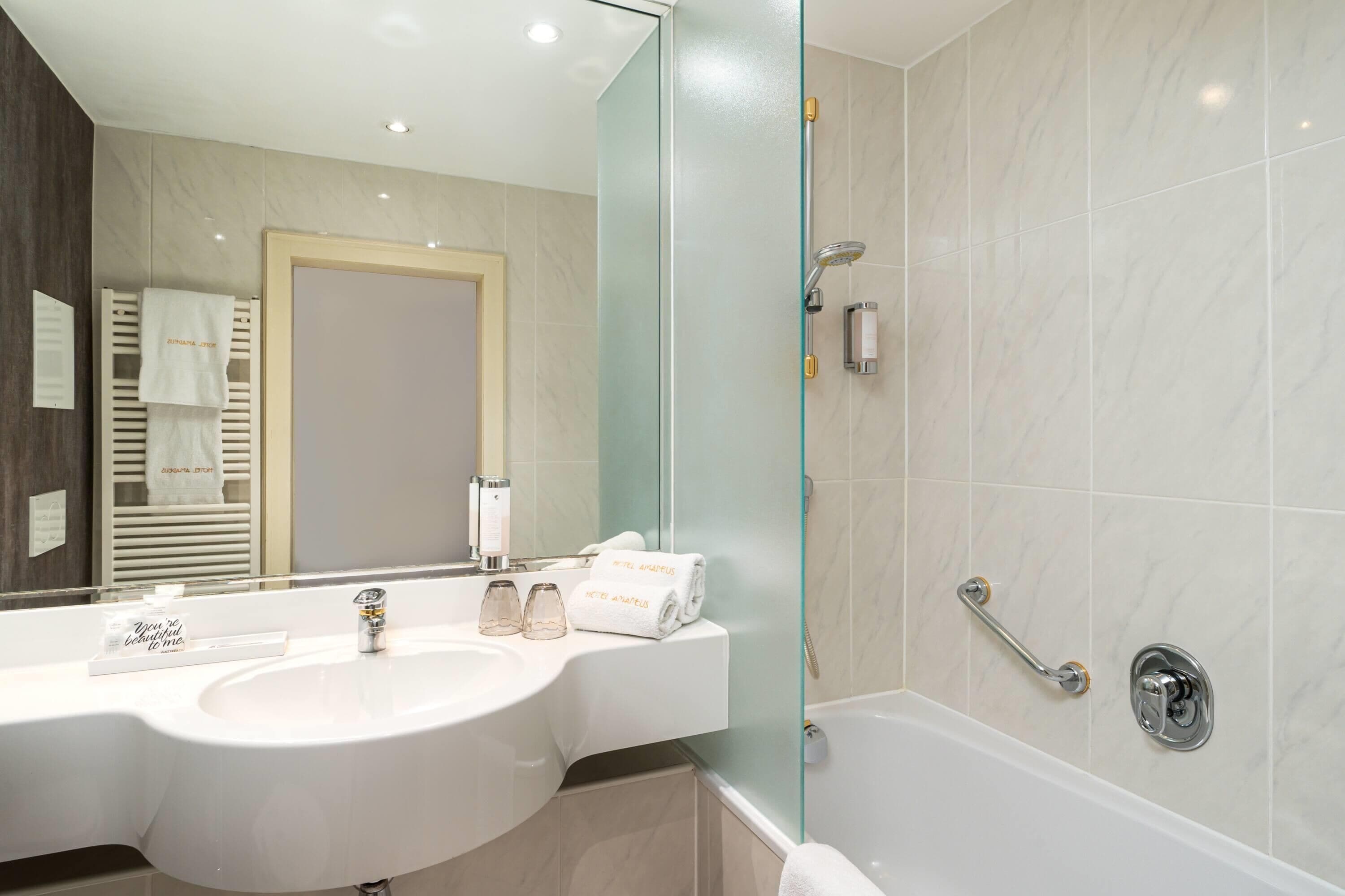Een moderne badkamer met een ruime wastafel, een douchecabine van glas en een ligbad.