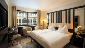A hotel room with a large bed, a desk, a chair, a TV, and a view of a building through the window. - elaya hotel vienna city center, Trademark by Wyndham (Vienna)