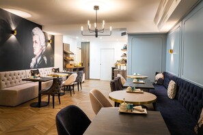 A modern dining area with a round table, a sofa, and a large painting on the wall. - elaya hotel vienna city center, Trademark by Wyndham (Vienna)
