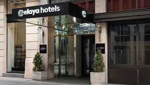 The exterior of Elaya Hotels with a glass entrance, a sign above the door, and two potted plants on either side. - elaya hotel vienna city center, Trademark by Wyndham (Vienna)