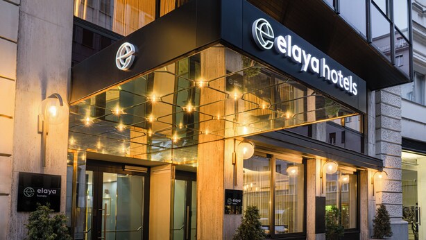 Fachada del edificio Elaya Hotels con señalización iluminada y acceso de vidrio.