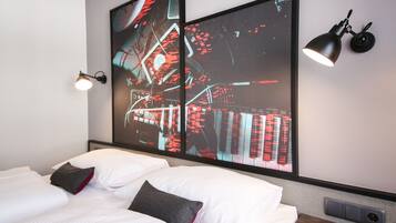 Un hotel moderno con una cama grande, un televisor empotrado que muestra un paisaje urbano, una lámpara de pared negra y un aire acondicionado integrado.