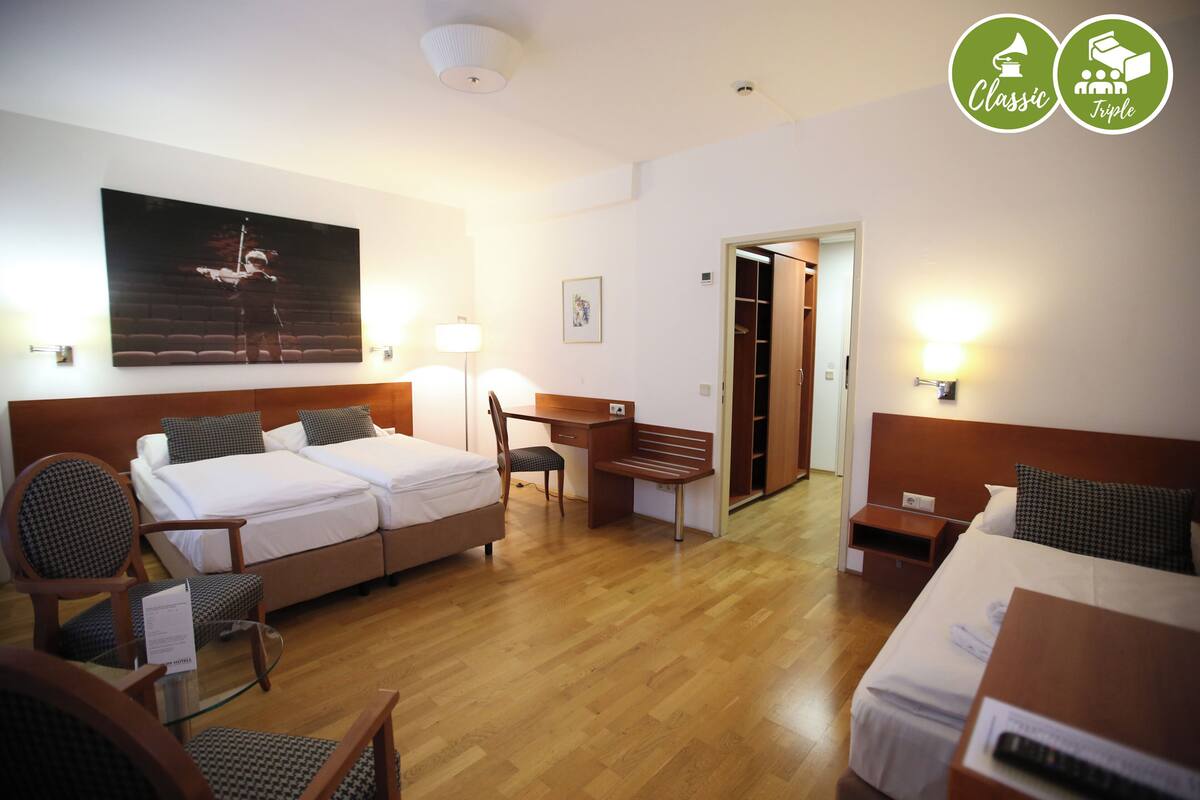 Une chambre d’hôtel avec deux lits, un bureau, une chaise et une armoire.