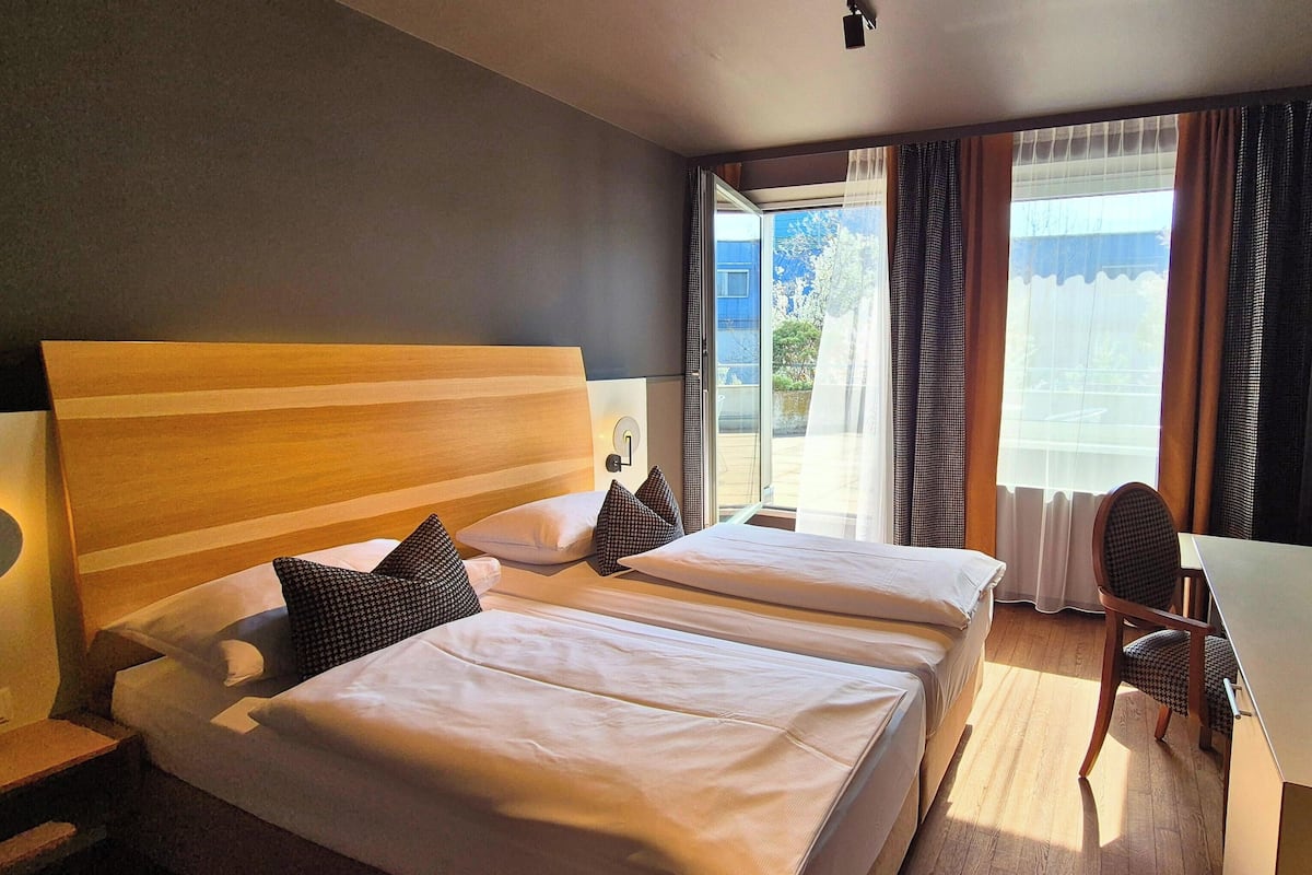 Une chambre d’hôtel avec deux lits, un bureau et une chaise.