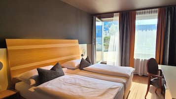 A hotel room with two beds, a desk, and a chair.