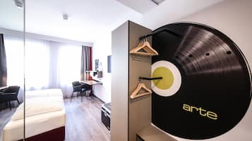 Camera d'albergo moderna con un letto, una scrivania, una sedia e un giradischi a parete di grandi dimensioni.