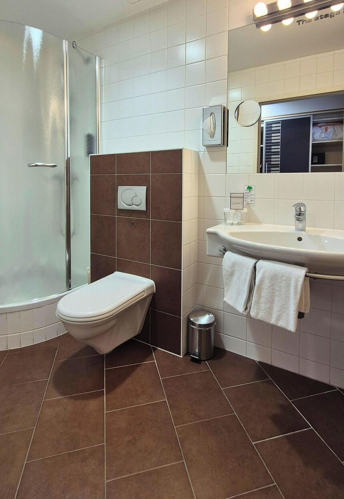 Een badkamer met douche, toilet, wastafel en spiegel.