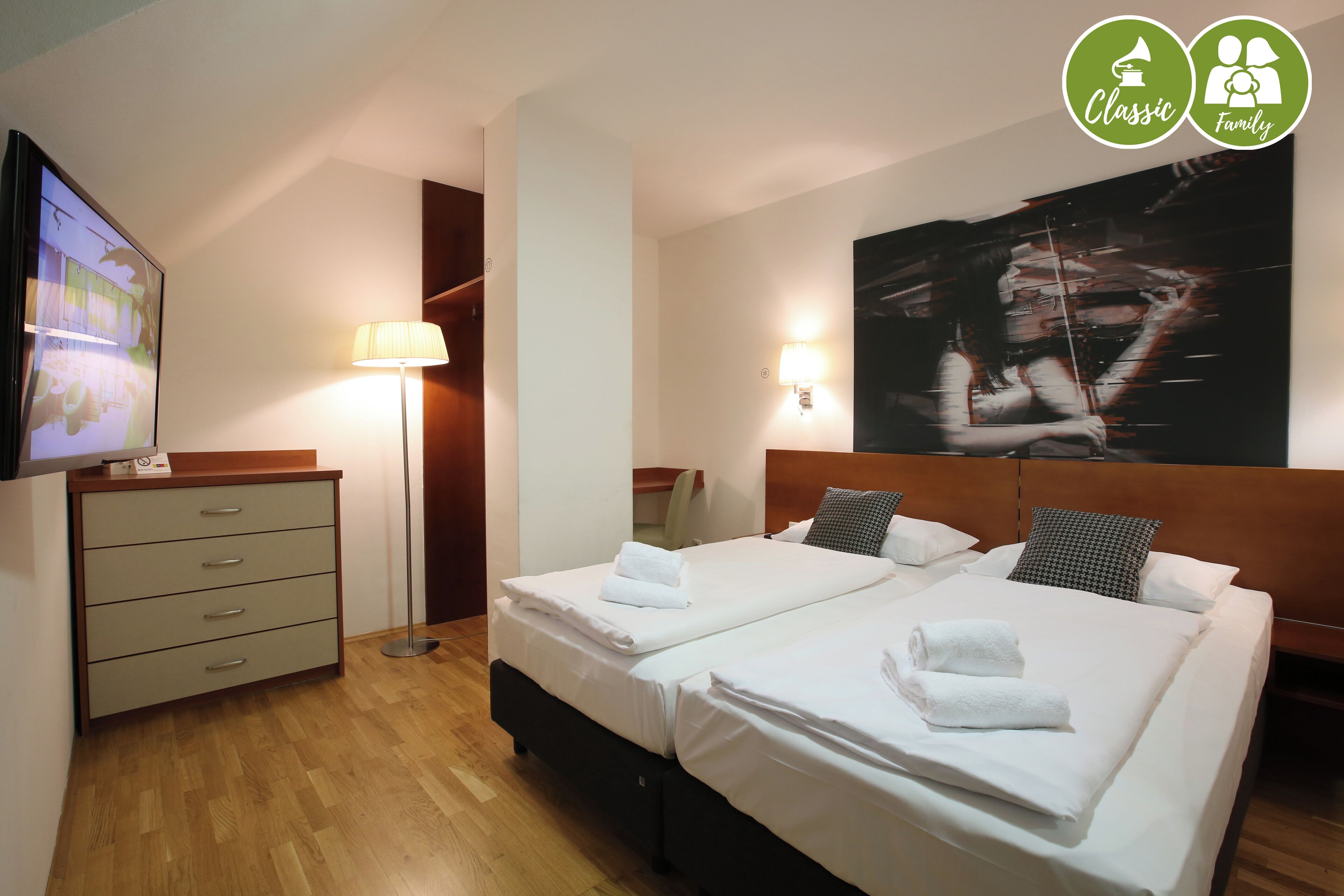 Une chambre d’hôtel avec deux lits, un bureau, une lampe et un téléviseur.