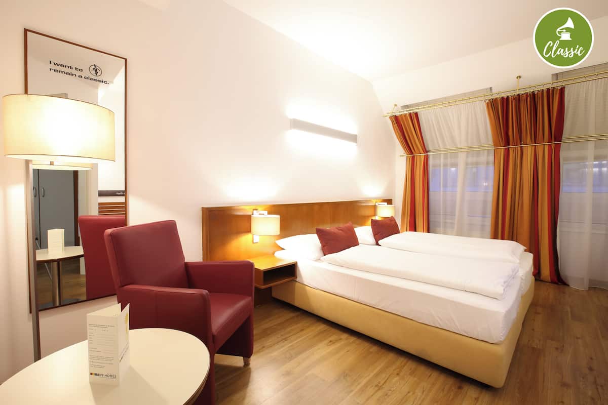 Une chambre d’hôtel avec un lit, une chaise, une table et une lampe.