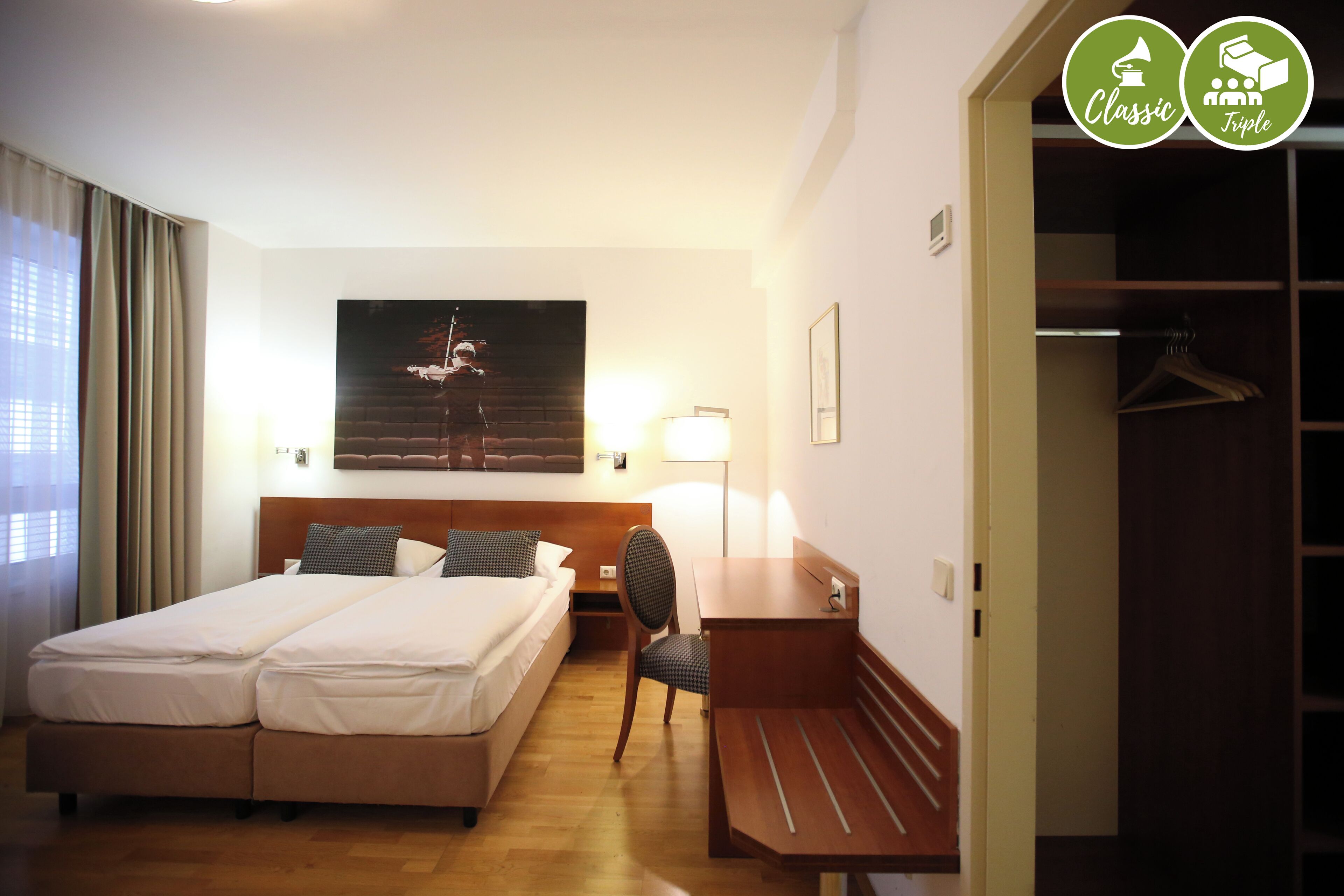 Camera d'albergo con un letto matrimoniale, una scrivania, una sedia, una lampada e un armadio.