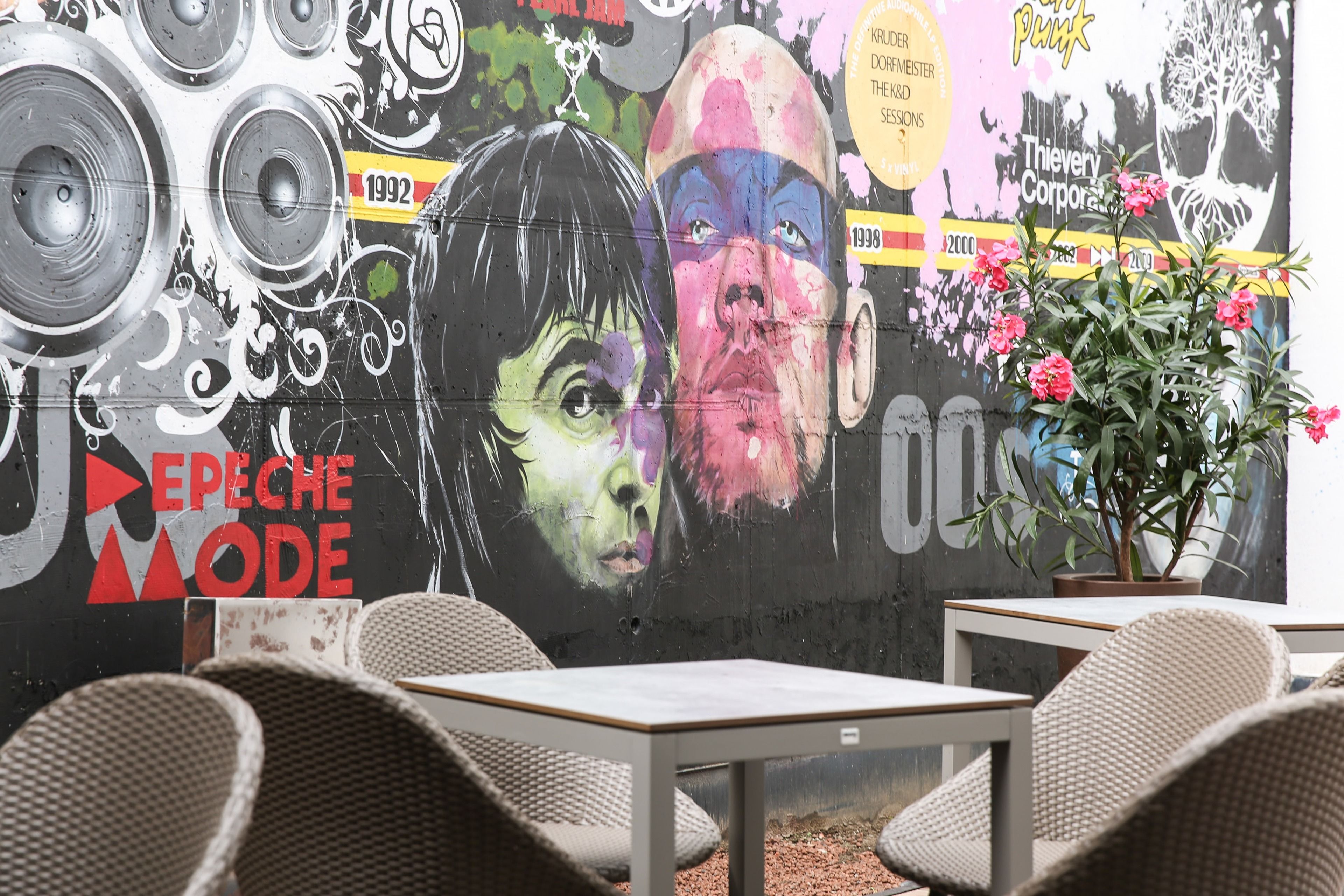 A wall with graffiti art, including a face and text, and a potted plant.