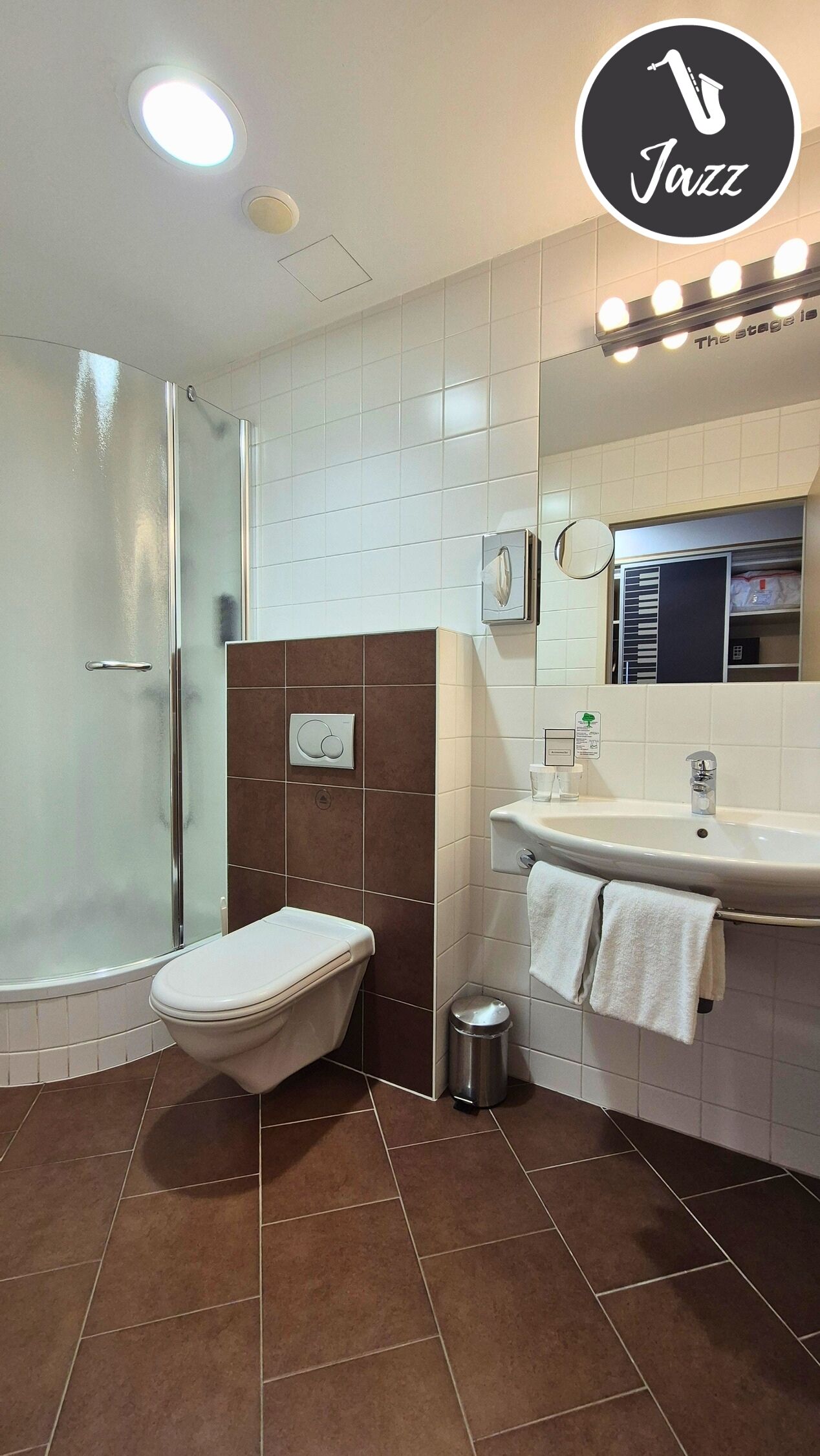 Une salle de bain moderne équipée de toilettes, d’une douche, d’un lavabo et d’un miroir.