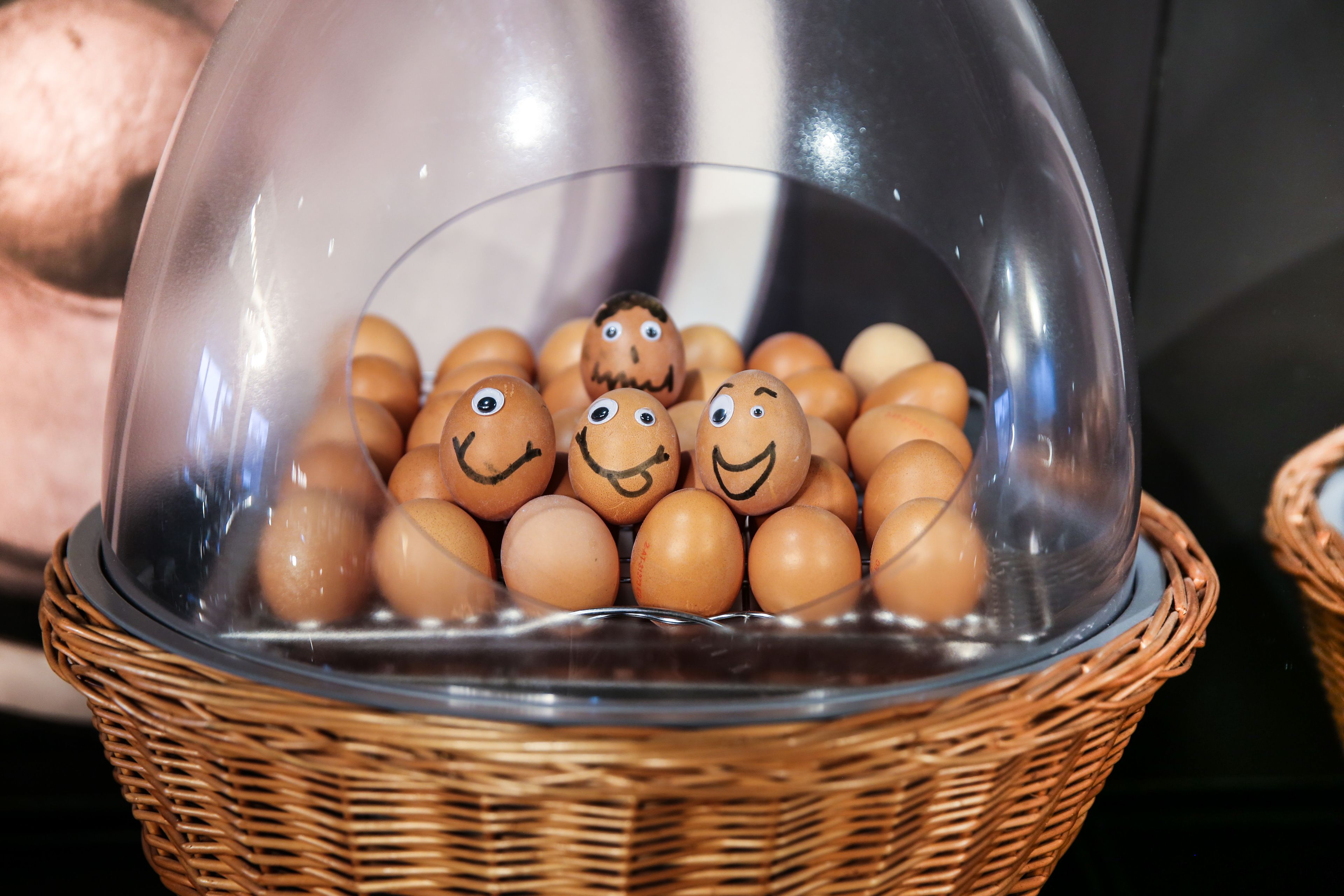 Een mand met eieren met gezichten, op een tafel gezet.