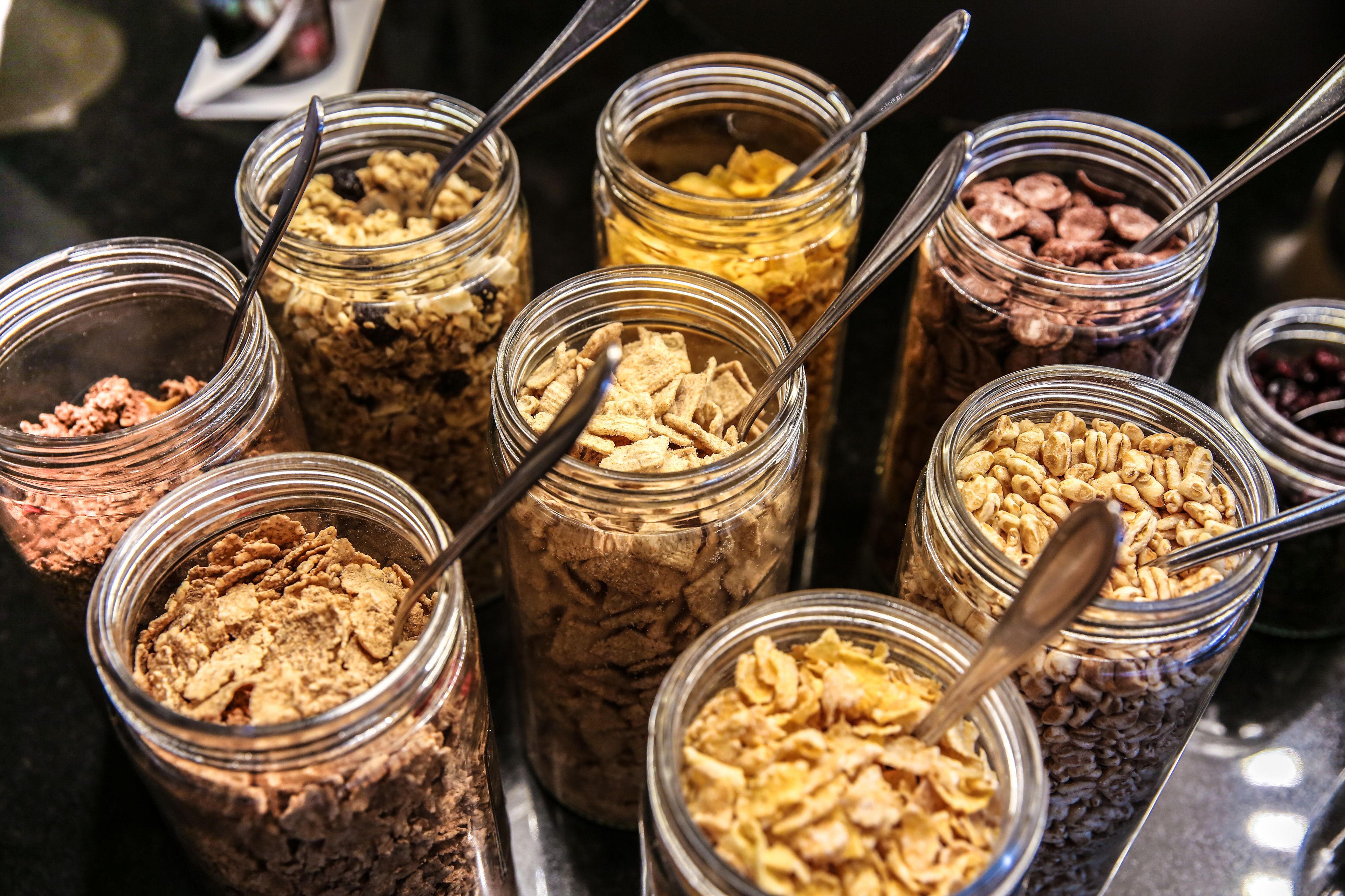 Diversas barras de cereal em potes com colheres.