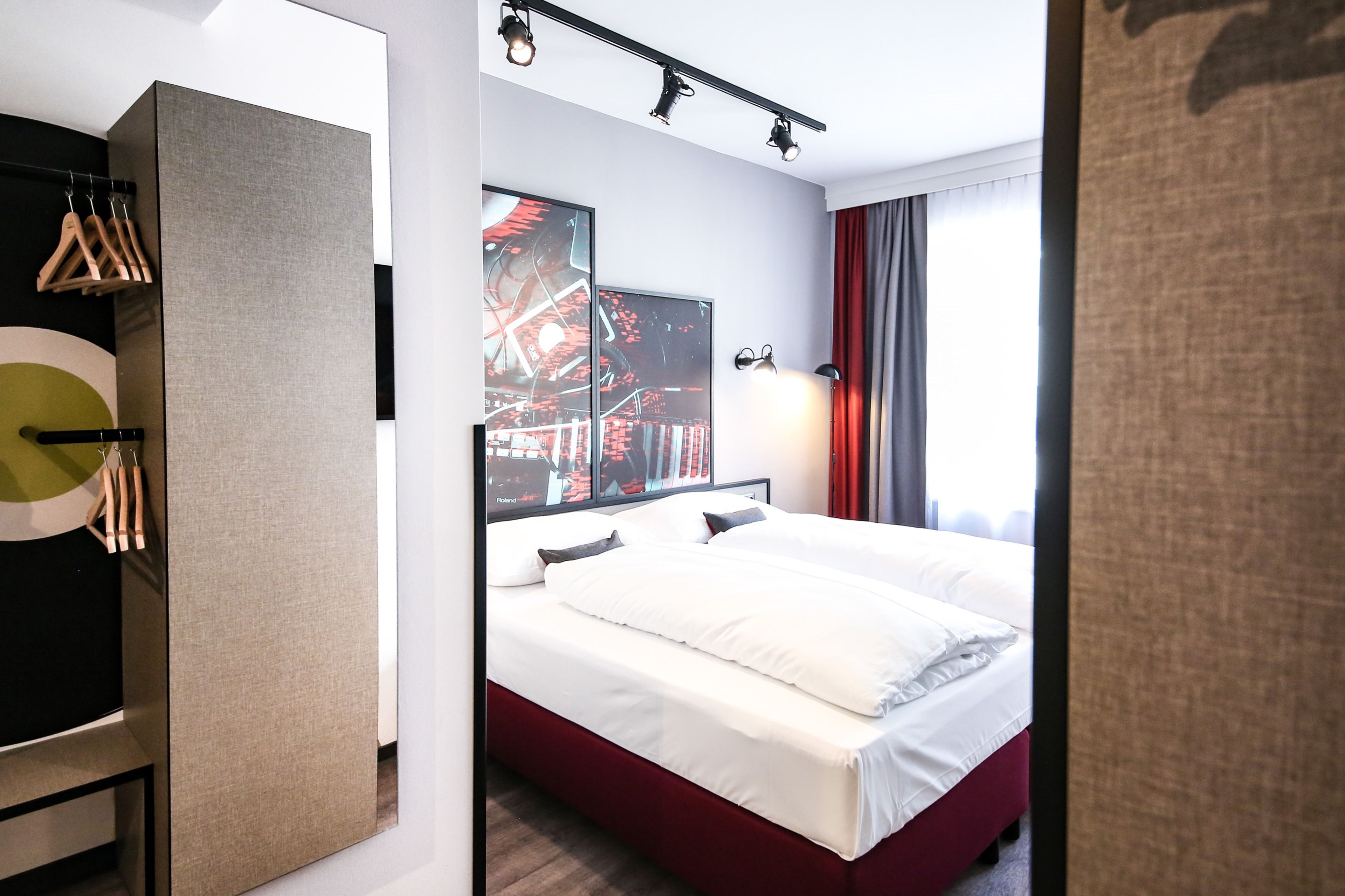 Ein Hotelzimmer mit Bett, Schrank, Spiegel und einem Vorhangfenster.