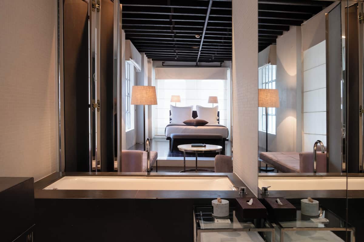 A modern bathroom with a large mirror, a bathtub, and a vanity with toiletries.