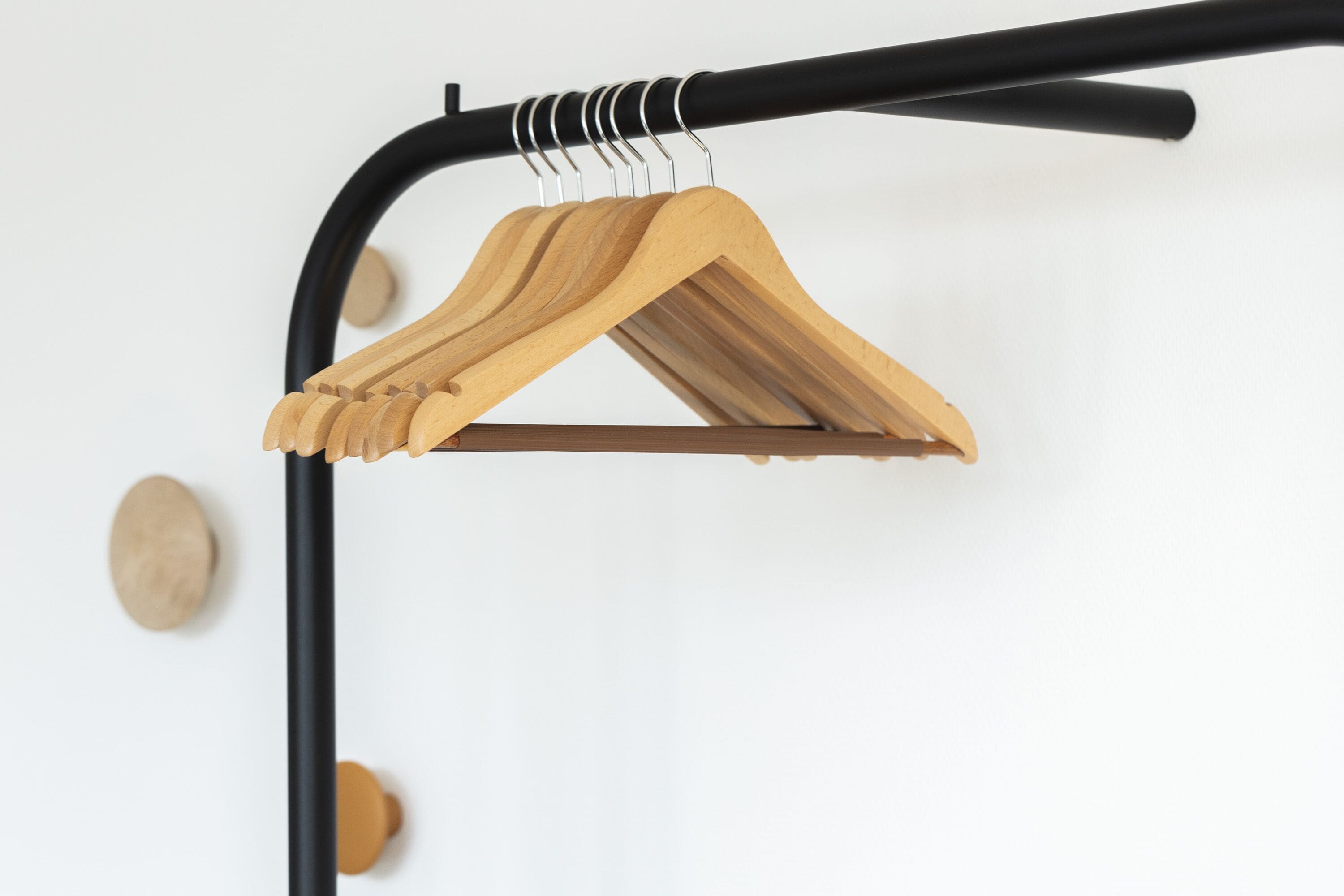 A wooden hanger on a black metal rack.