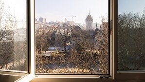 A view through a window of a cityscape with a prominent tower and construction cranes in the background. - Fred Hotel Hauptbahnhof (Zürich)