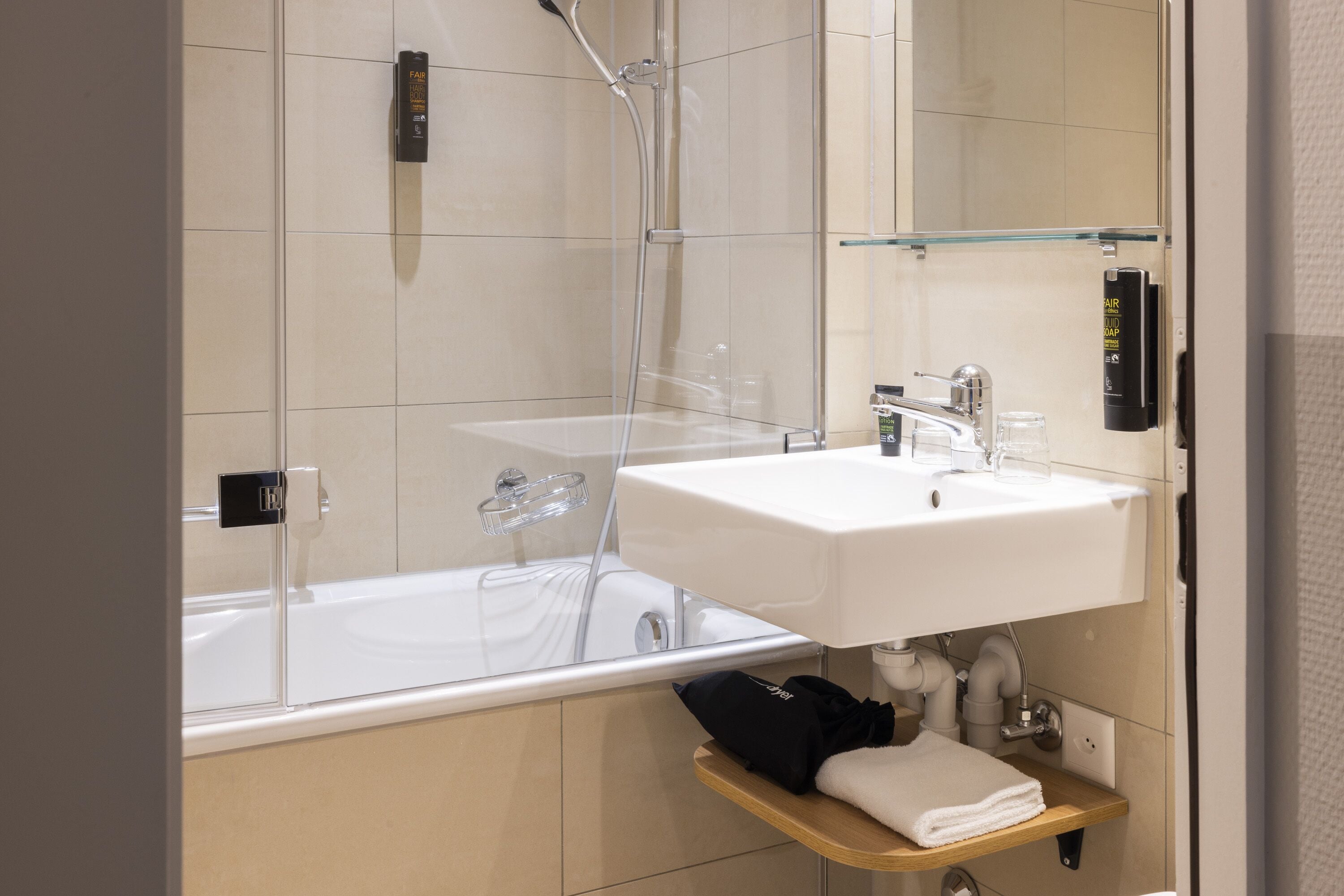 A modern bathroom with a glass-enclosed shower, a white sink, and a towel rack.