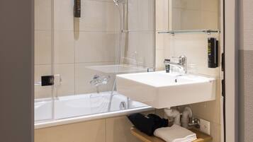 A modern bathroom with a glass-enclosed shower, a white sink, and a towel rack.