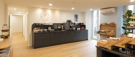 A modern kitchen with a central island, built-in appliances, and a view of the city through large windows.